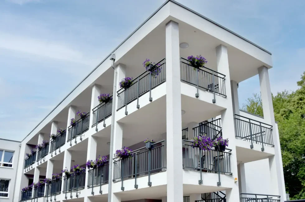 Außenansicht des Senioren- & Pflegeheims Haus Mühlberg in Krettnich mit Balkonen und Blumenkästen vor grüner Umgebung